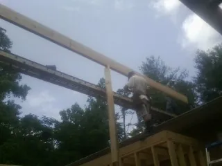 Carpenter setting a ridge beam over a new addition frame — Ice Dam Removal by Roofing Brothers in Hallsboro
