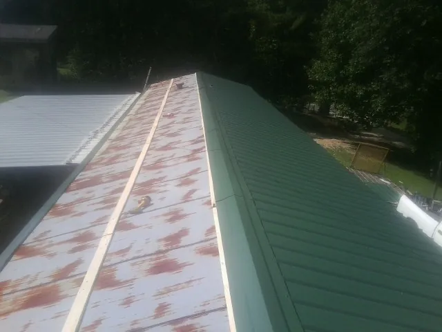 Old rusted panels beside newly installed green metal roofing — Wind Damage Roof Repair by Roofing Brothers in Hallsboro
