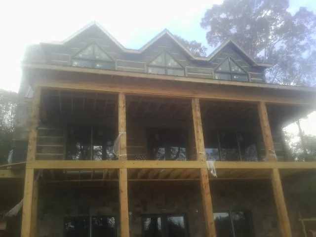 Dormers and porch framing on a large log home under construction — Roof Coating work by our crew in Hallsboro