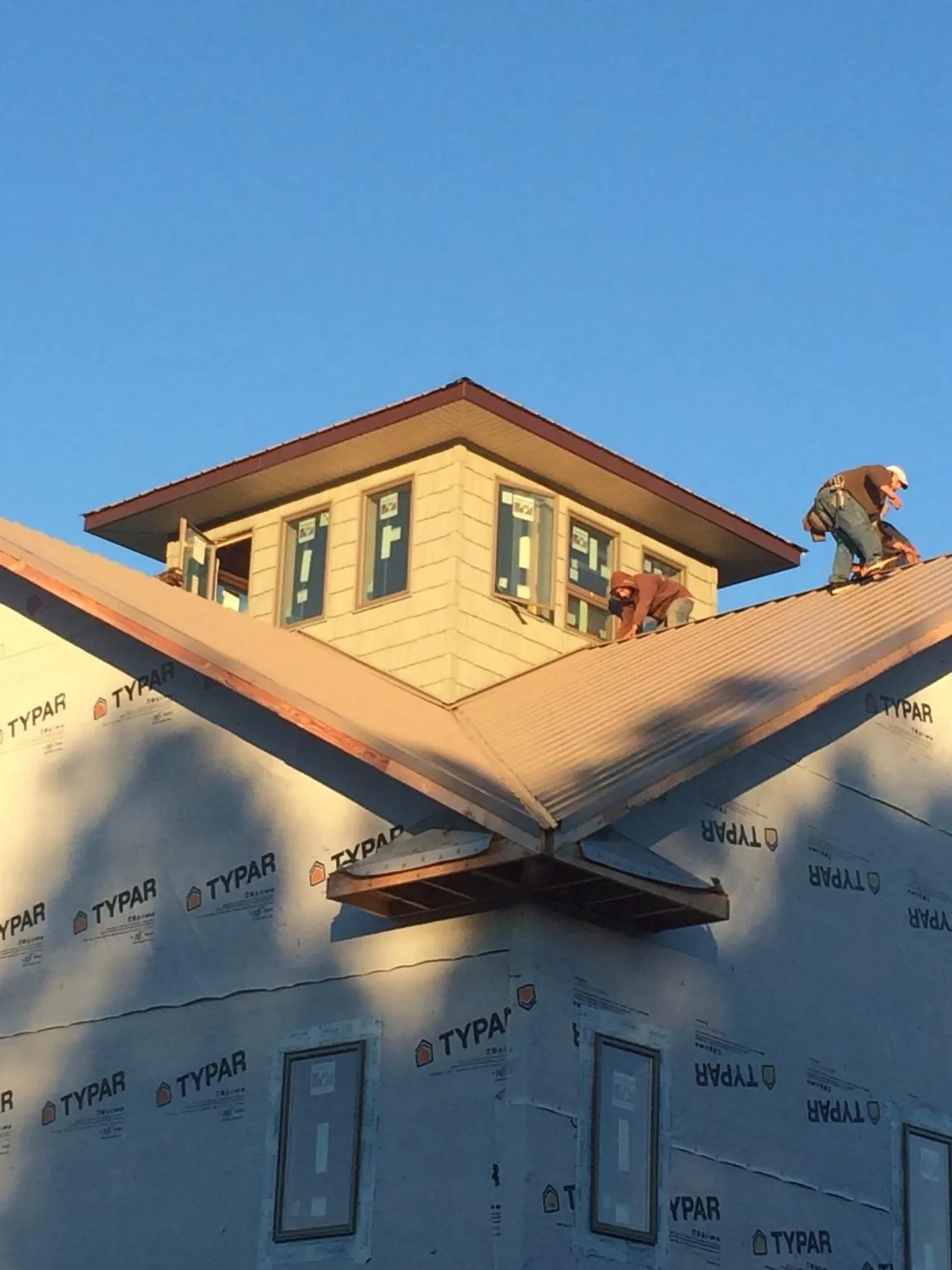 Roofers working around a rooftop cupola on a new metal roof at sunset — Roof Waterproofing in Hallsboro by Roofing Brothers